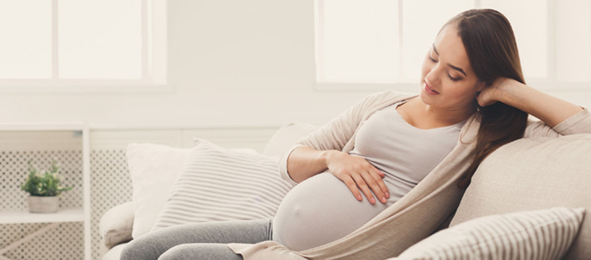 Pregnant woman sitting cradling bump